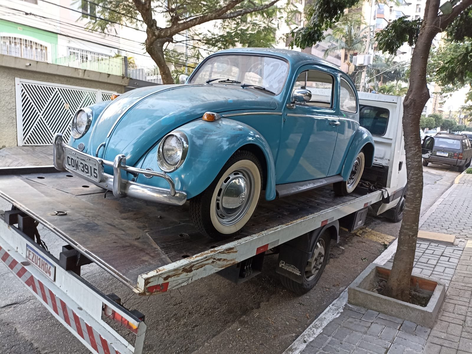 Volkswagen Fusca azul clássico transportado em guincho plataforma